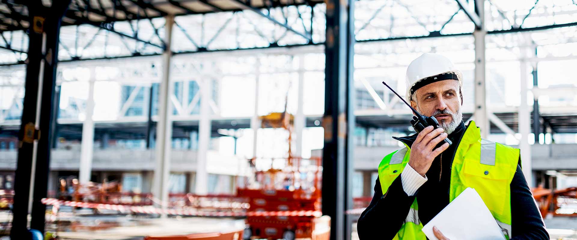 Site manager communicating on radio inside industrial building