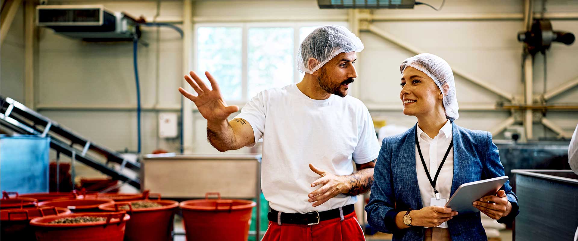  Un homme en blouse blanche et charlotte inspecte une ligne de production
