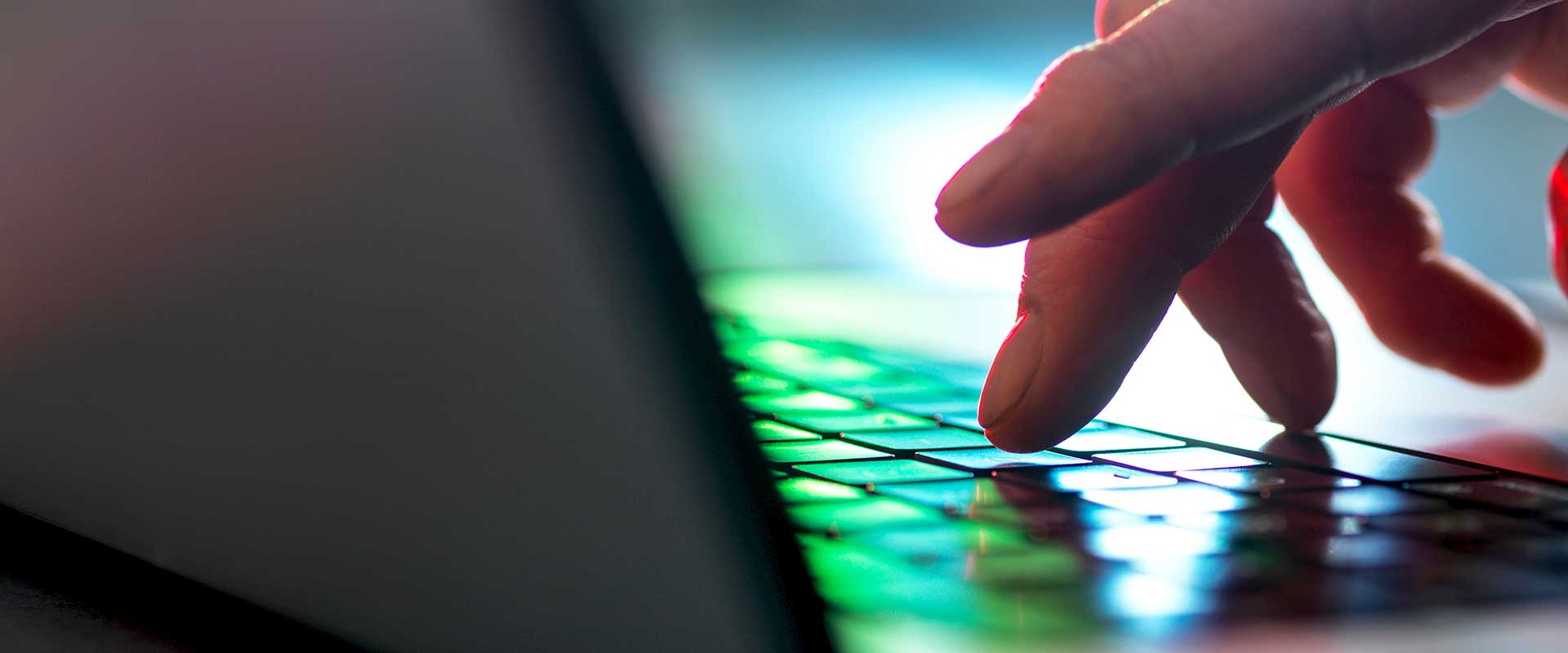 Prim plan cu mâini care tastează pe o tastatură iluminată