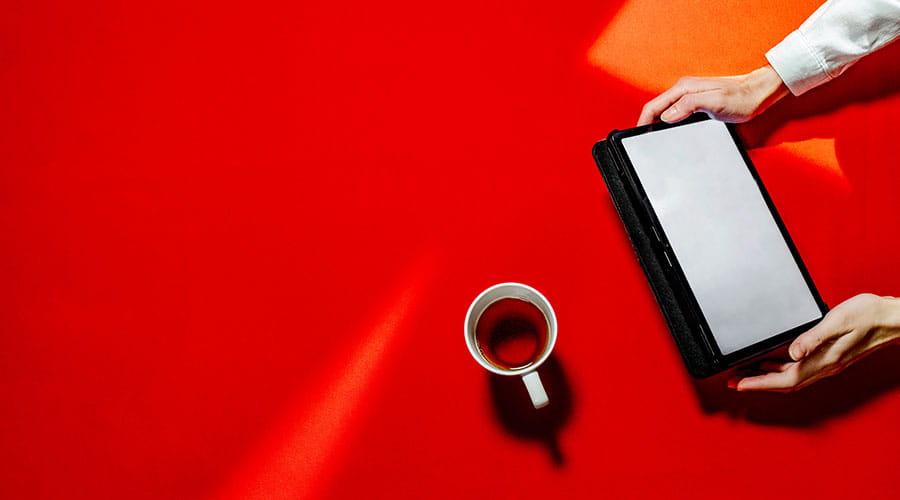 Tablet en koffiekopje op rode achtergrond