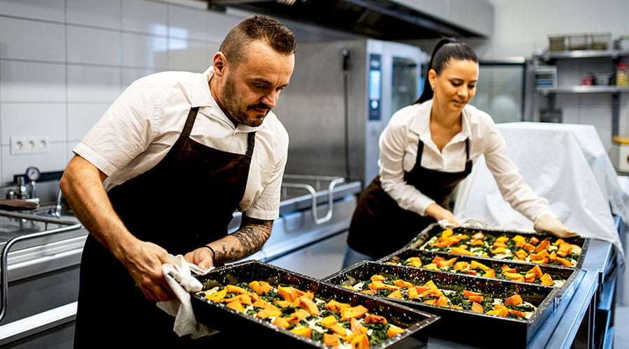 Chefs retirant des plateaux de nourriture du four dans la cuisine