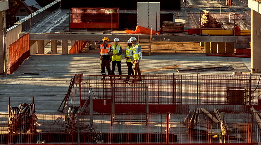 Muncitori în construcții colaborând pe un șantier mare