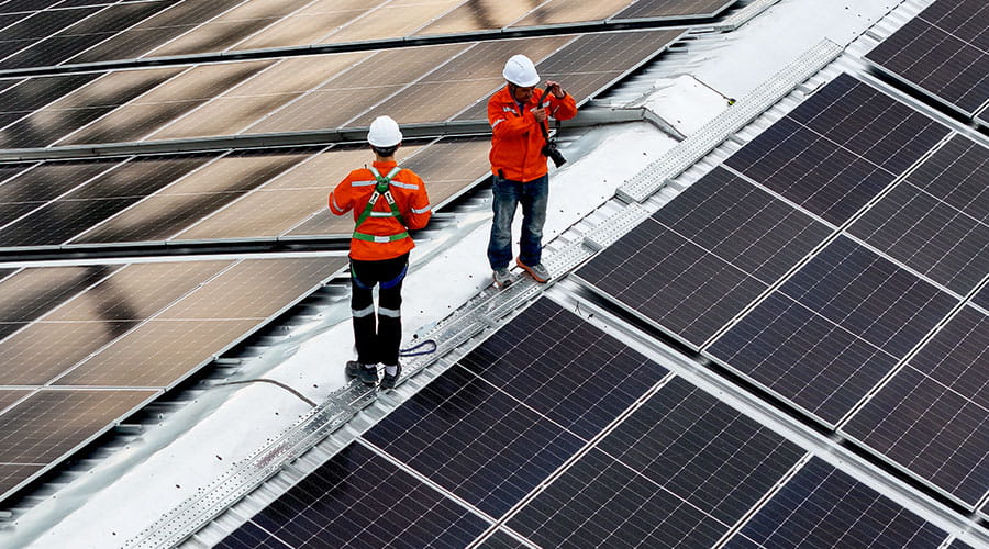 Workers installing solar panels on rooftop