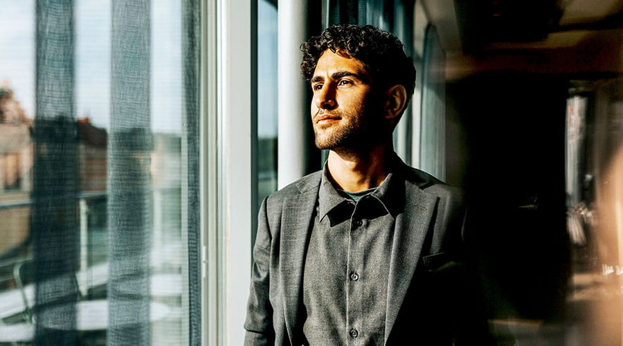 Man staat in kantoor en kijkt uit het raam