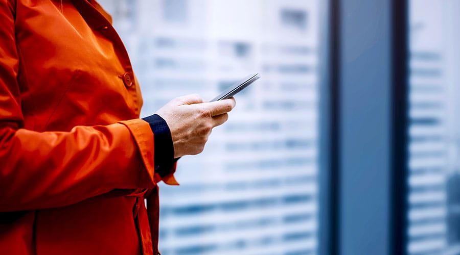 Person using smartphone in front of office building