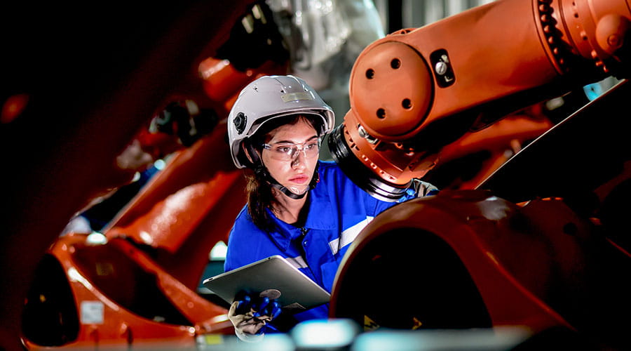 Travailleur manipulant un bras robotique en production
