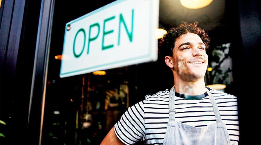 Employé de magasin tournant le panneau ouvert sur la porte Employé de magasin tournant le panneau ouvert sur la porte