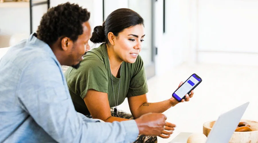 Two people reviewing information on a smartphone and laptop Two people reviewing information on a smartphone and laptop