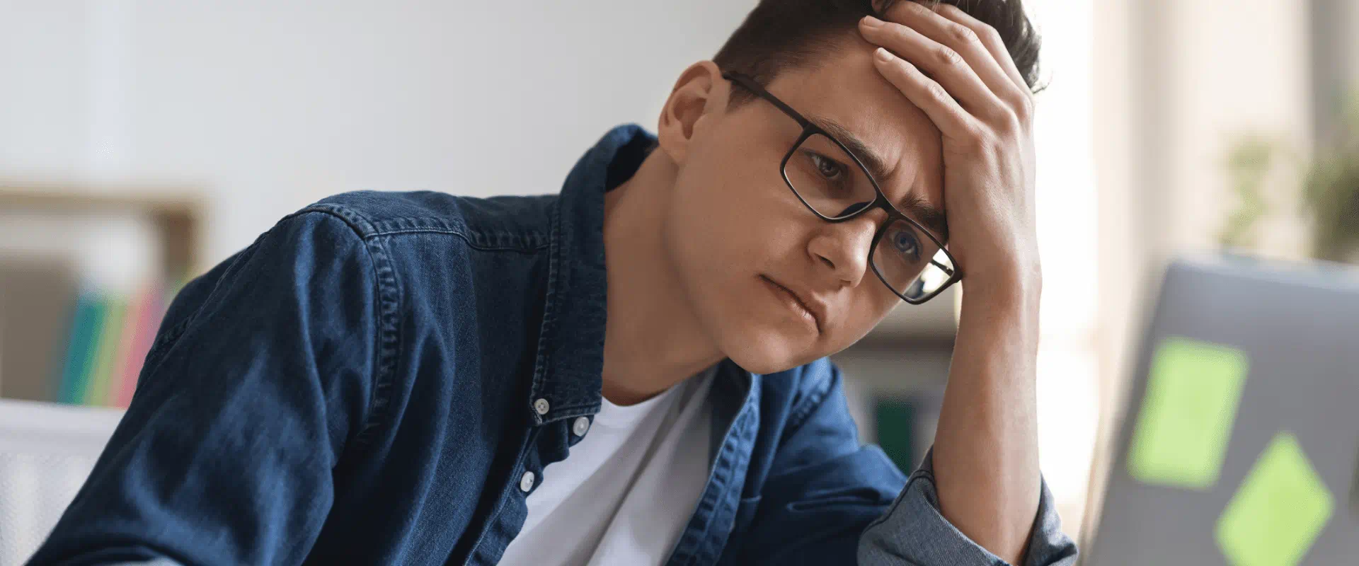 A young person sits at a desk, looking overwhelmed. A young person sits at a desk, looking overwhelmed.