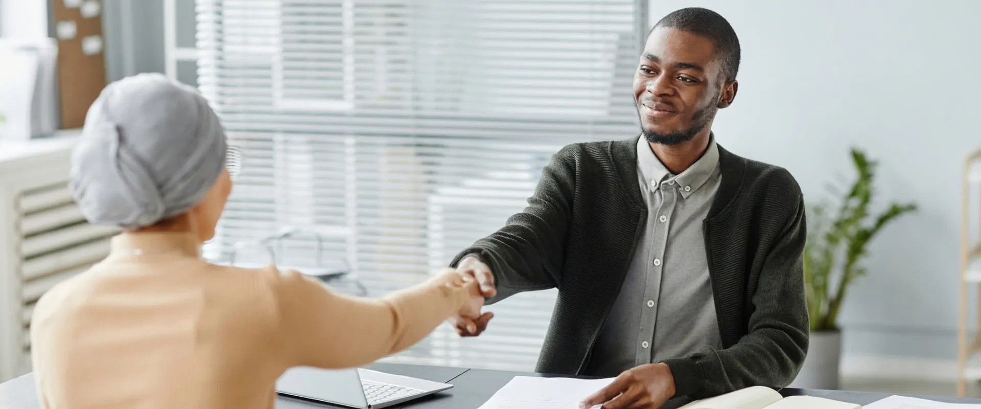 A professional extending a handshake during a business meeting in a modern office. A professional extending a handshake during a business meeting in a modern office.