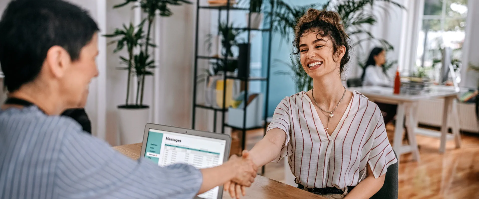 A smiling woman shaking hands with a recruiter during a job interview in a modern office setting. A smiling woman shaking hands with a recruiter during a job interview in a modern office setting.