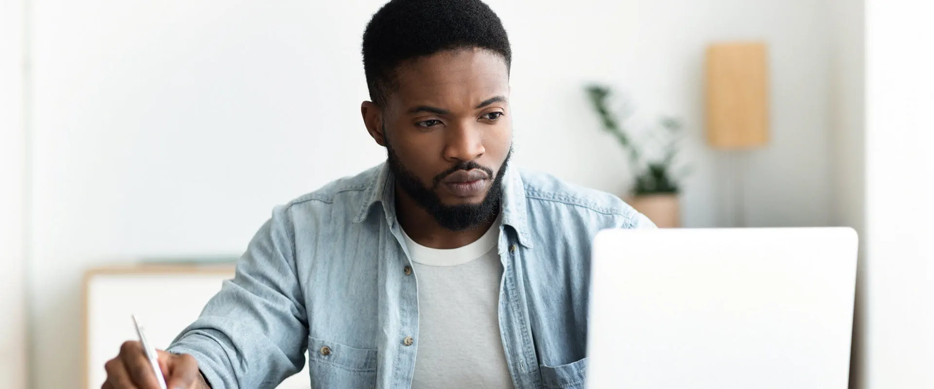 A focused professional working intently on a laptop in a modern office setting.