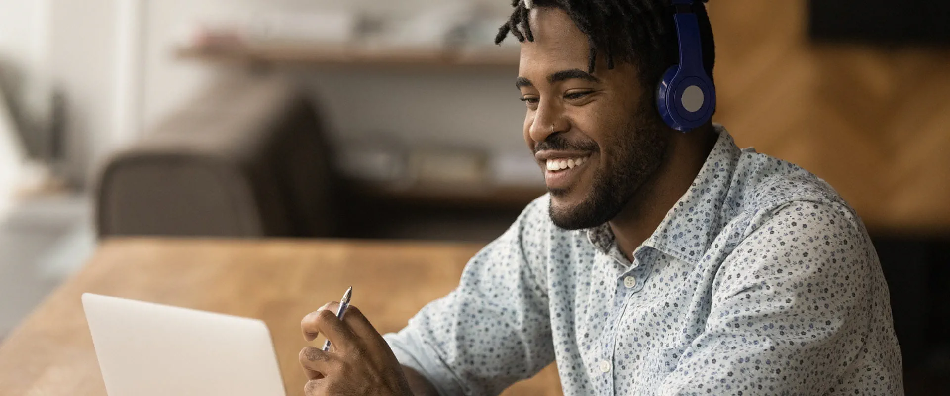 Close up smiling person wearing headphones using laptop, looking at screen. Close up smiling person wearing headphones using laptop, looking at screen.