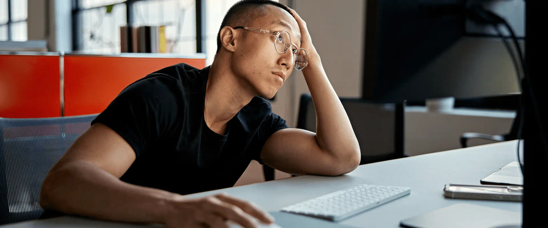 A young worker sits at a computer, looking frustrated A young worker sits at a computer, looking frustrated