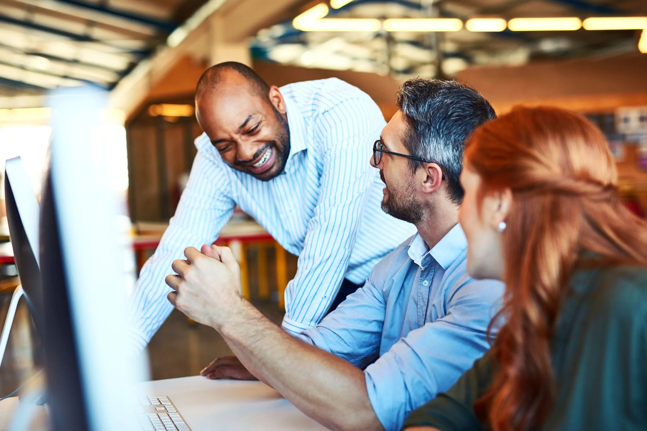 Three coworkers collaborate at a desk Three coworkers collaborate at a desk