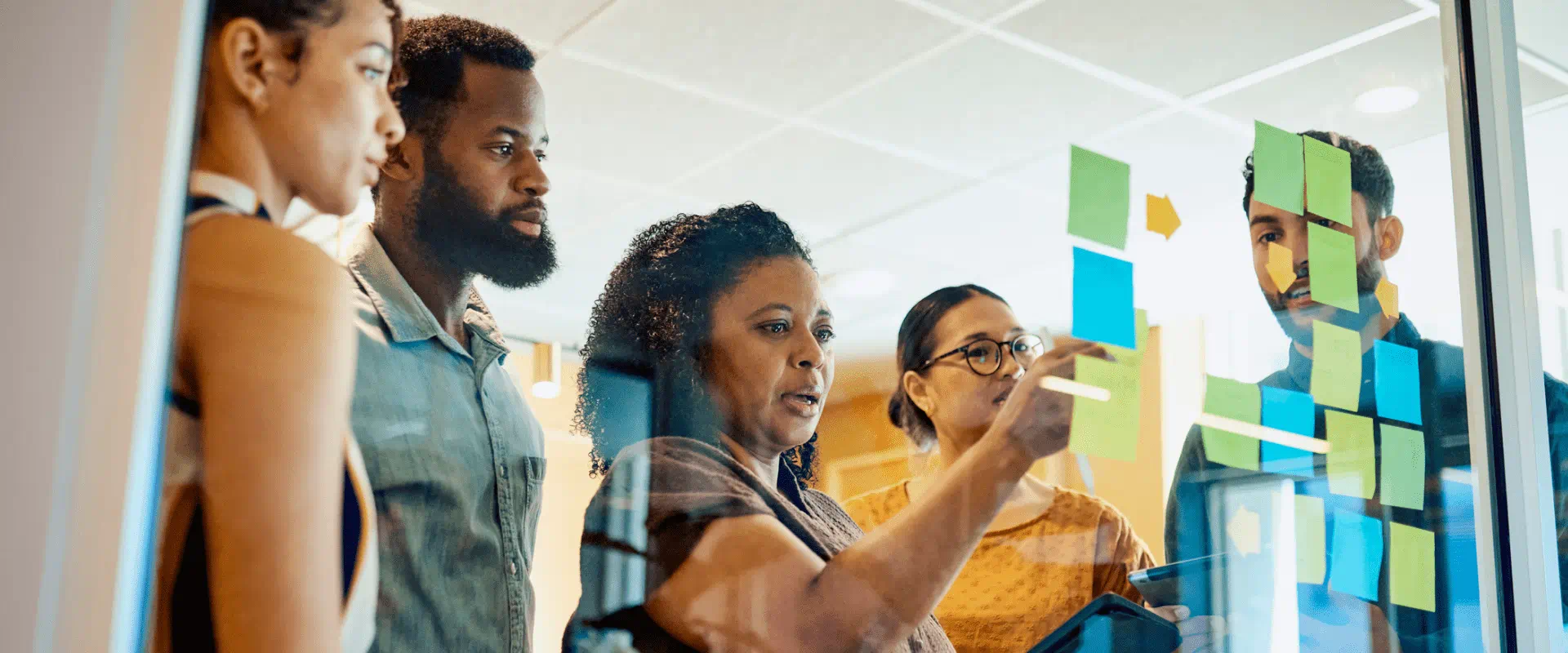 A group of people in an conference room huddle around a planning wall.