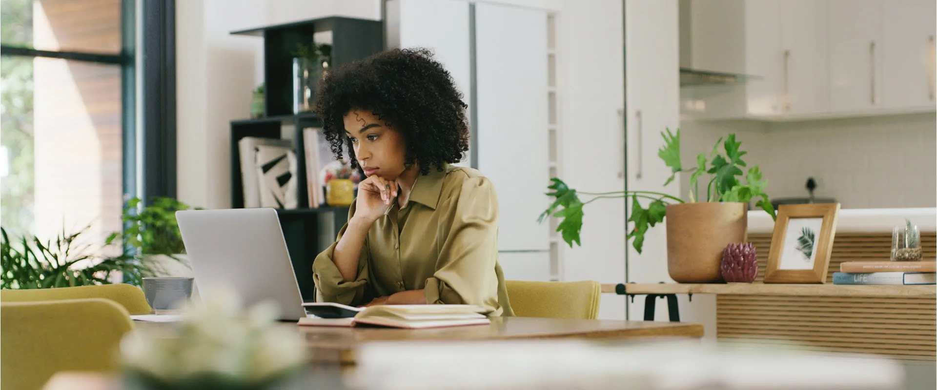 A woman sits at home looking pensively at her laptop. A woman sits at home looking pensively at her laptop.