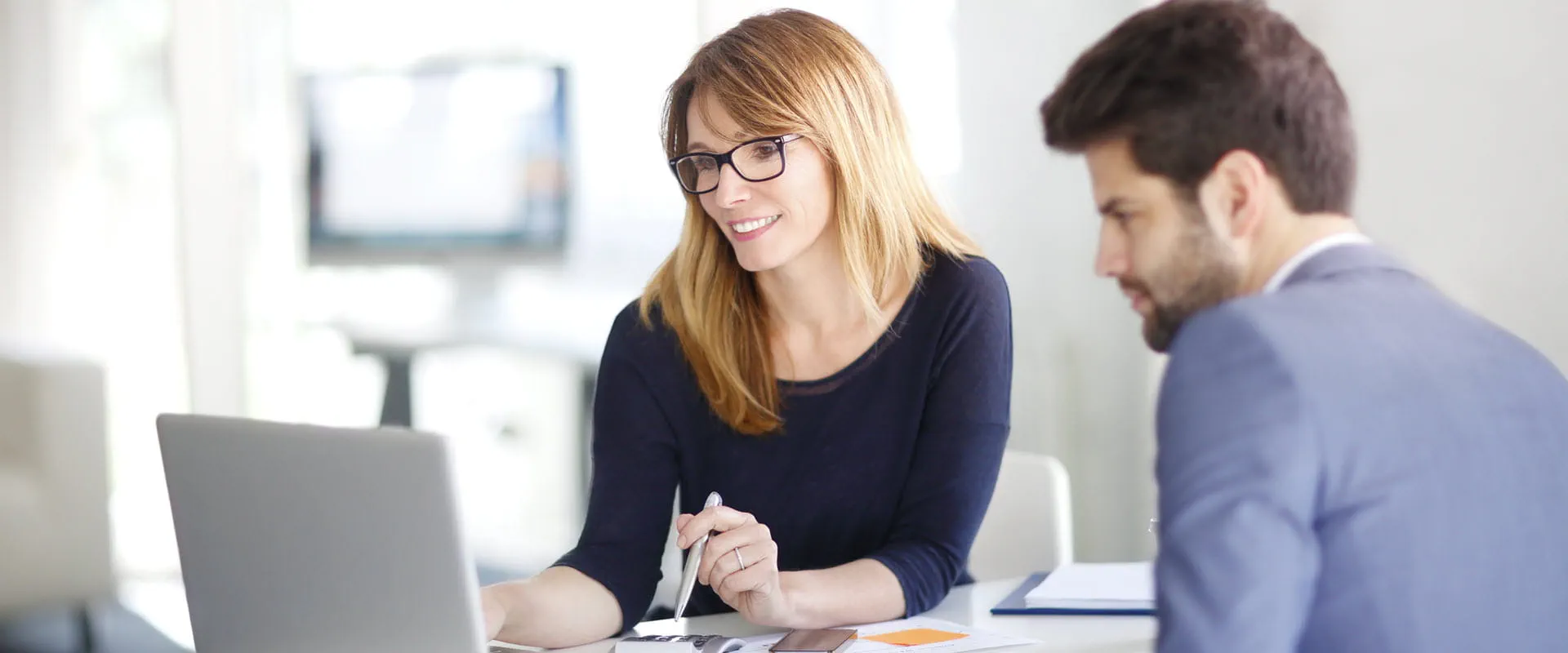 Investment advisor sitting at office in front of computer and consulting with client.
