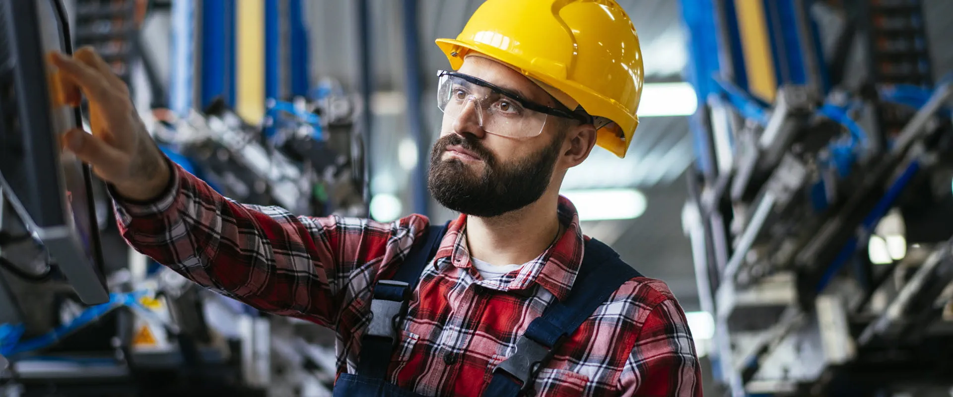 Factory worker wearing safety glasses and yellow hardhat.