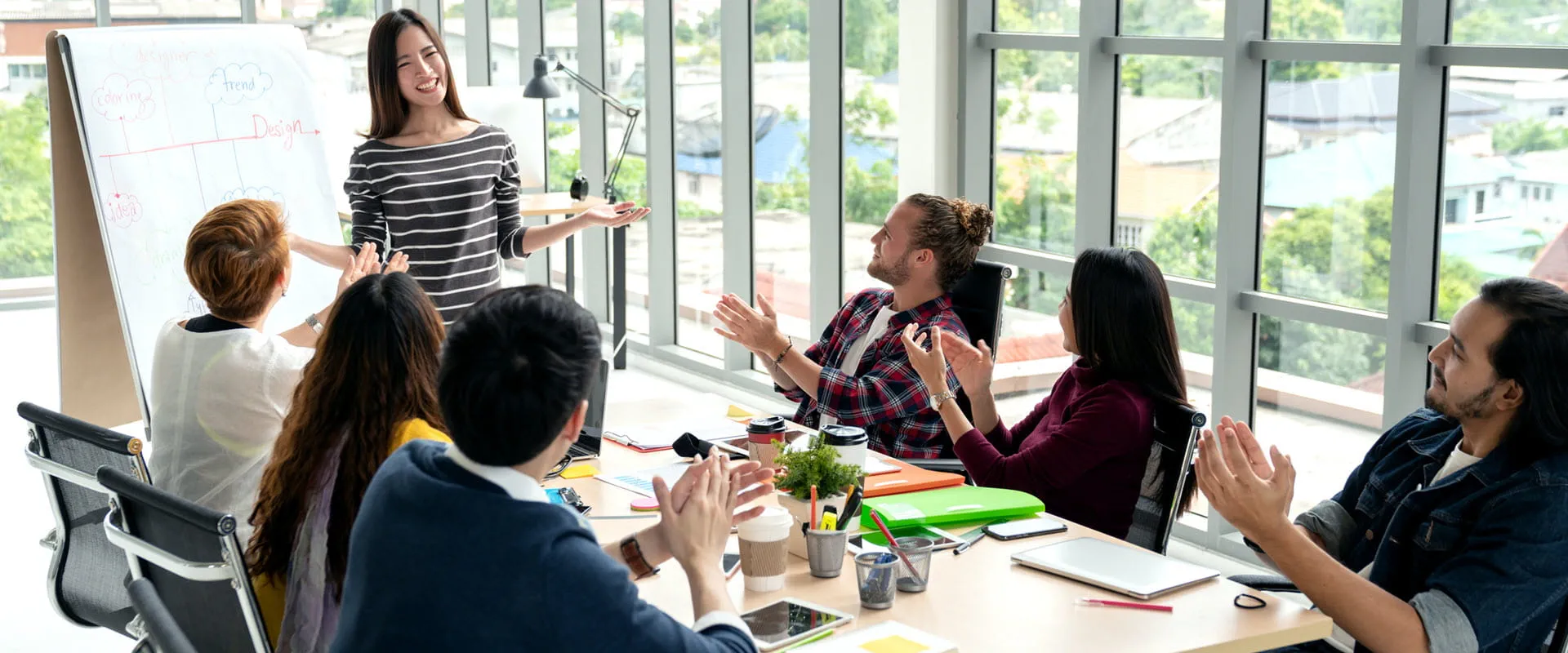 A group of people in a modern office applauding a colleague who is presenting at a whiteboard during a team meeting. A group of people in a modern office applauding a colleague who is presenting at a whiteboard during a team meeting.