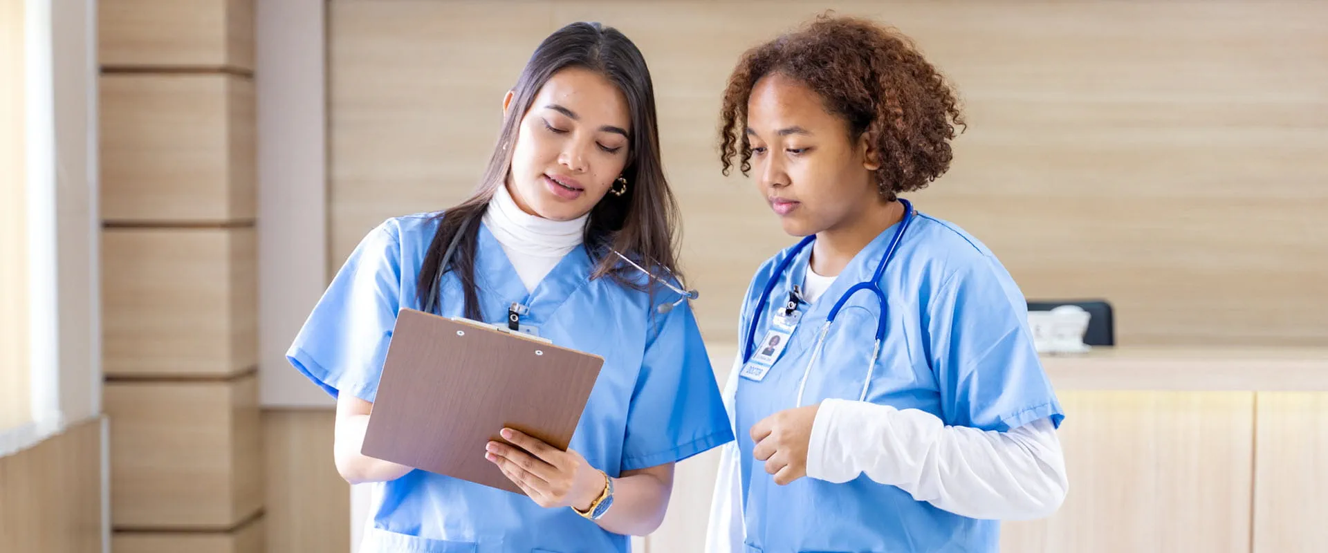 Two nurses consulting while viewing a patient chart.