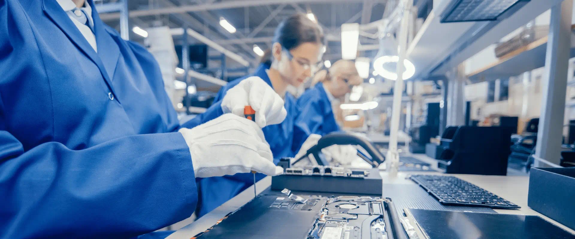 Workers in an assembly line work on computer chips Workers in an assembly line work on computer chips