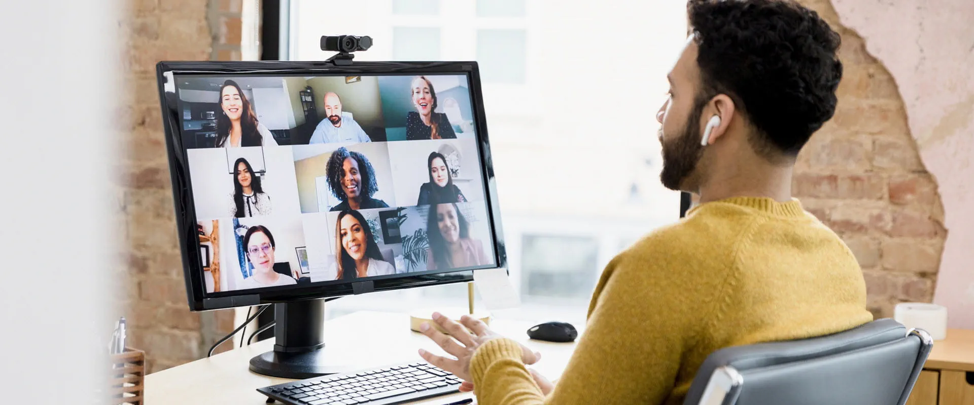 Person sitting at a desk in an office meets virtually with team members. Person sitting at a desk in an office meets virtually with team members.