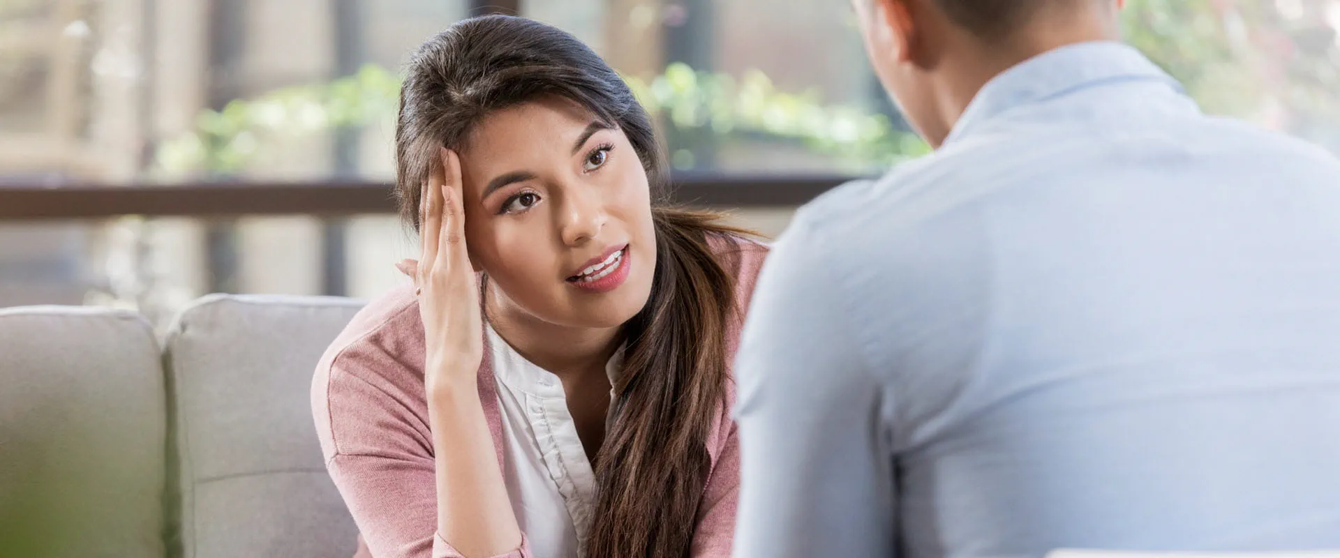 A concerned individual in a pink cardigan engaged in a thoughtful conversation with another person in a light blue shirt. A concerned individual in a pink cardigan engaged in a thoughtful conversation with another person in a light blue shirt.