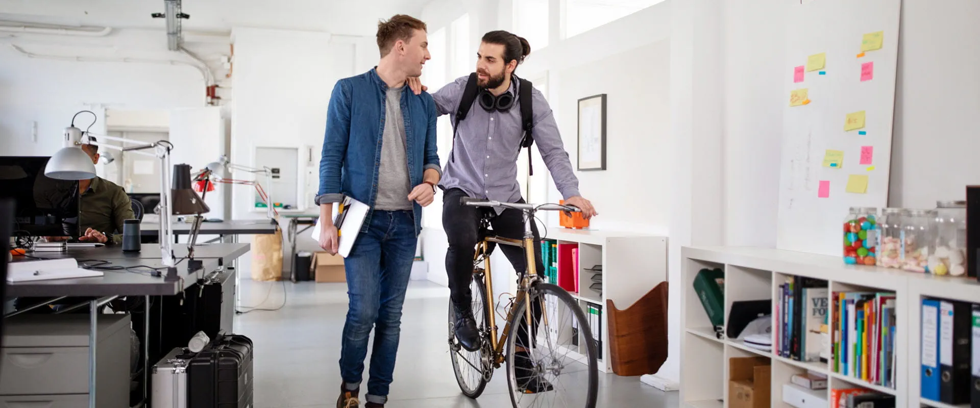 Office workers discussing work in the office, one colleague on a bicycle. Office workers discussing work in the office, one colleague on a bicycle.