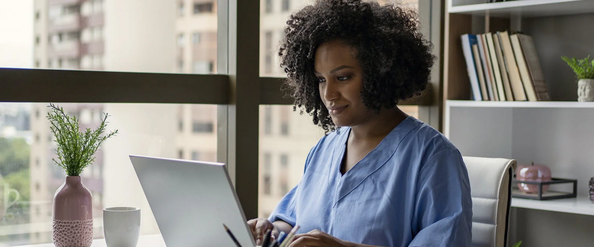 Nurse sitting at a desk, working on a laptop. Nurse sitting at a desk, working on a laptop.