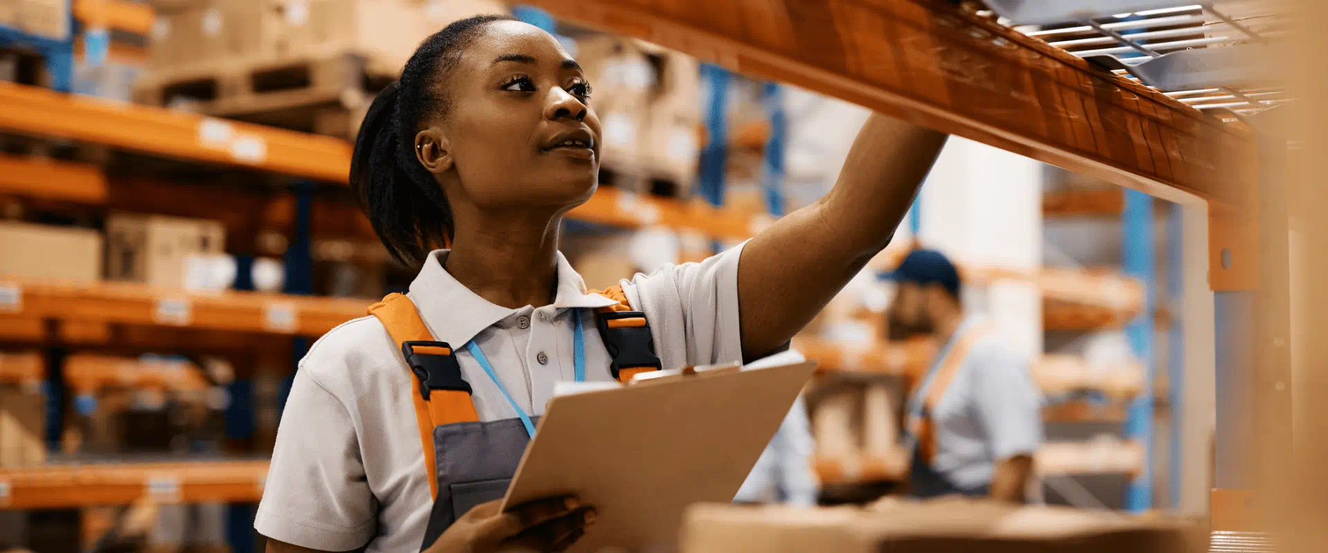 A worker in a warehouse looks at a high shelf