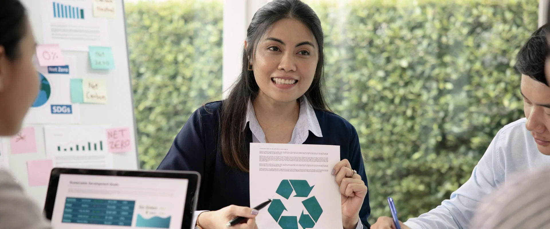 Person in meeting holding eco-friendly graphic.