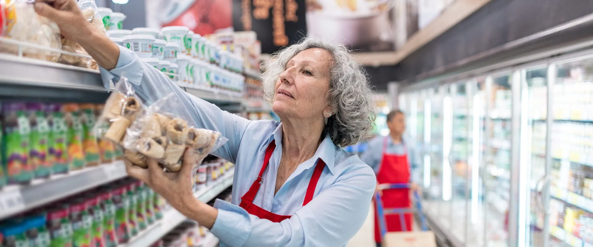 A senior worker stocking shelves in a grocery store. A senior worker stocking shelves in a grocery store.