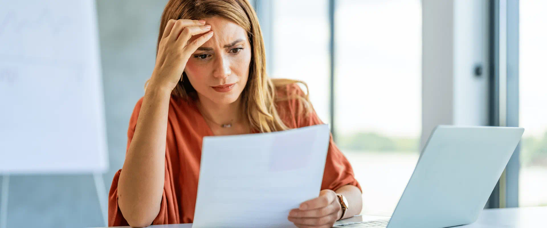 Professional at their desk, looking at a piece of paper and seeming frustrated.