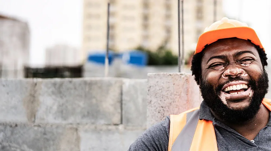 Worker in safety gear smiling in outdoor environment Worker in safety gear smiling in outdoor environment