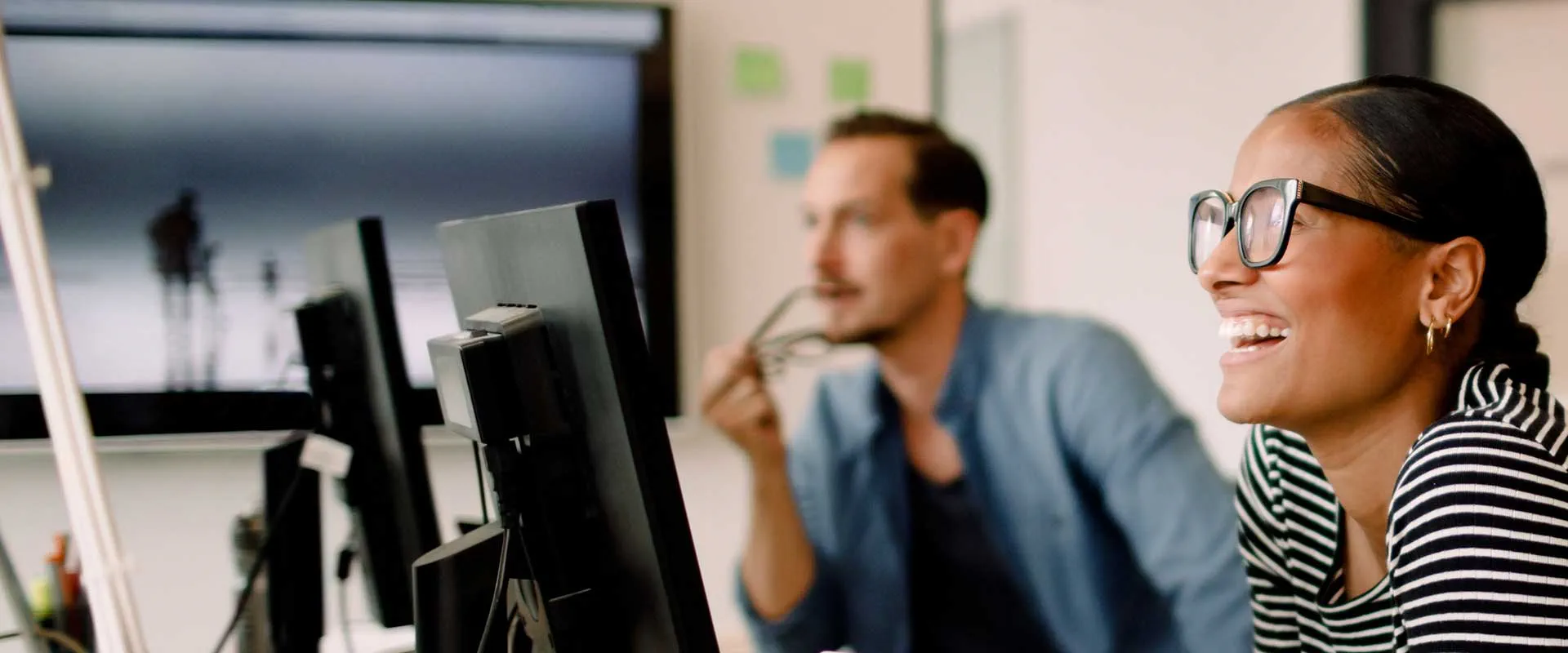  Colleagues smiling and working together at computer screens