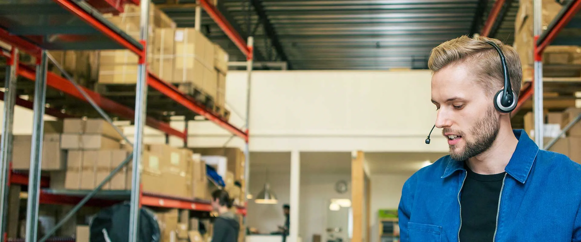  Warehouse worker wearing a headset managing stock in a logistics environment