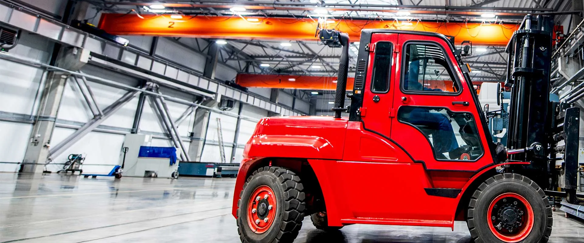 Red industrial forklift operating inside warehouse facility Red industrial forklift operating inside warehouse facility