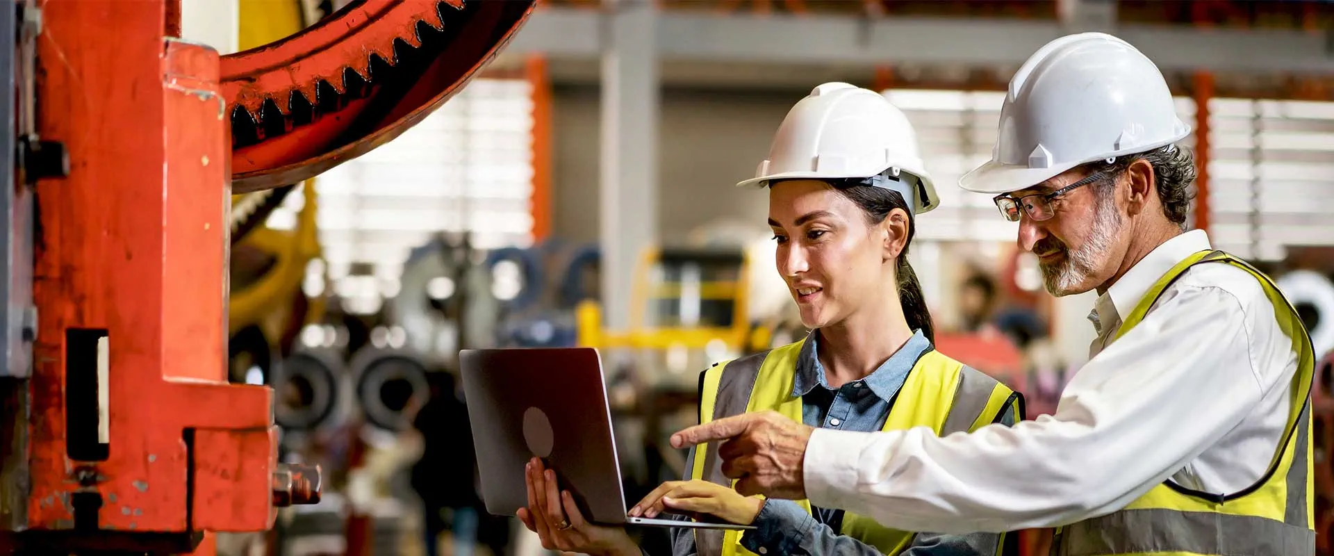Engineers reviewing data on laptop in factory setting Engineers reviewing data on laptop in factory setting