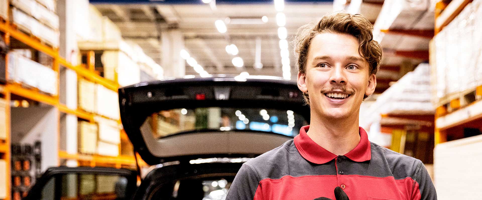  Retail worker standing in warehouse with open vehicle trunk