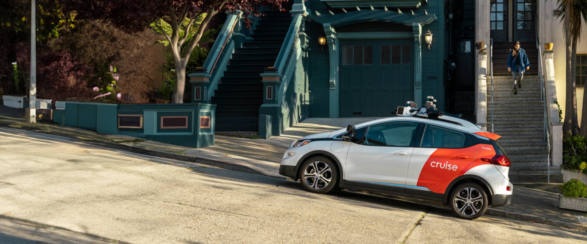 Autonomous vehicle from Cruise parked on a residential street with colorful houses in the background.