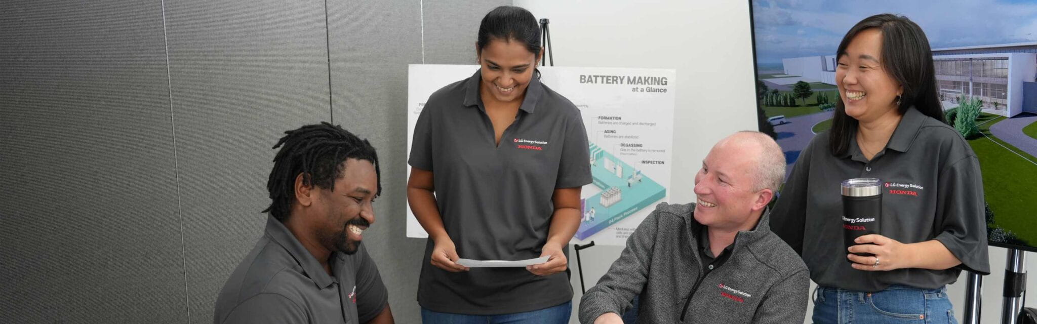 Four colleagues in company-branded polos share a laugh during a meeting