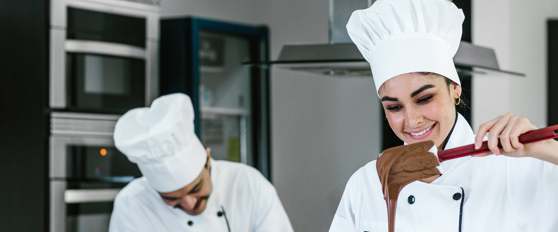 Person in white chef's hat stirring chocolate.