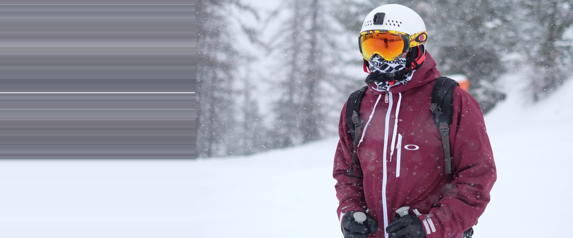 A skier in winter gear, wearing a helmet and goggles, standing on a snowy mountain.