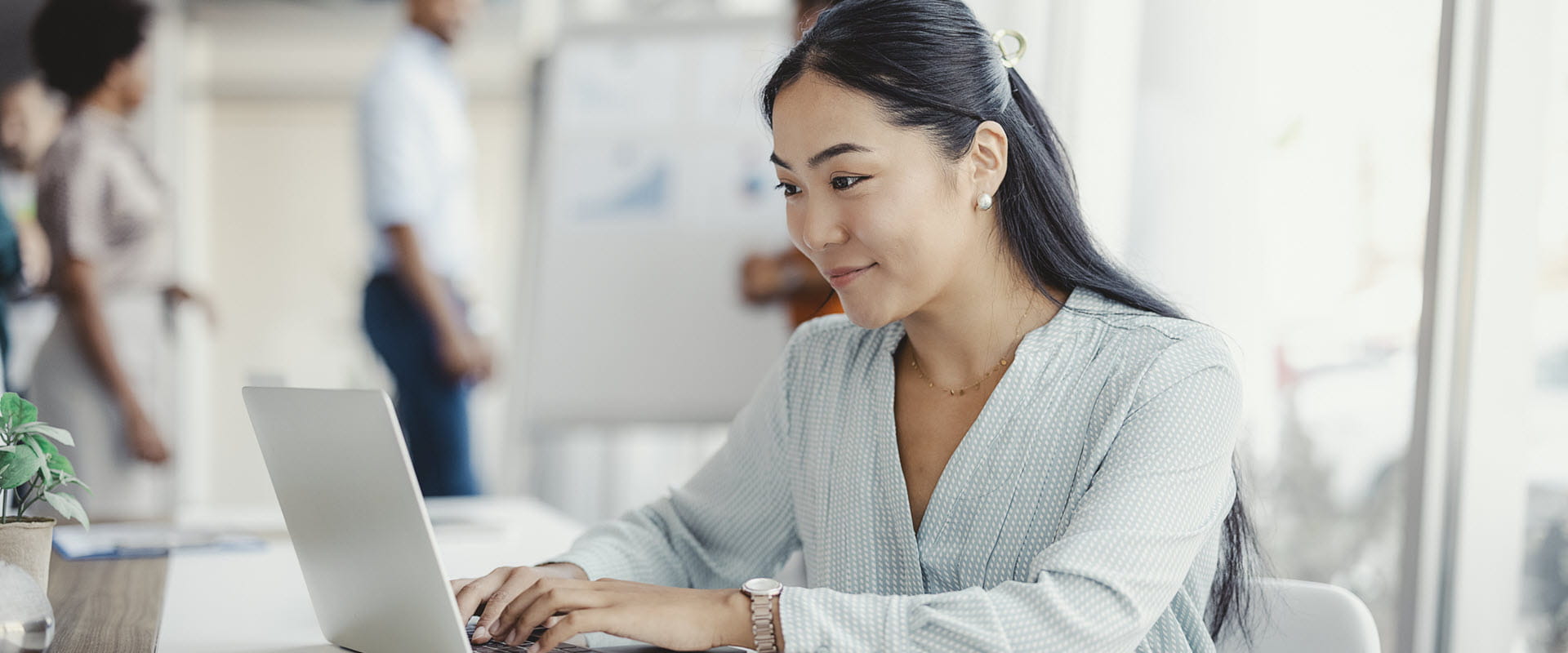 An individual in an office sits at a desk, typing at a laptop. An individual in an office sits at a desk, typing at a laptop.