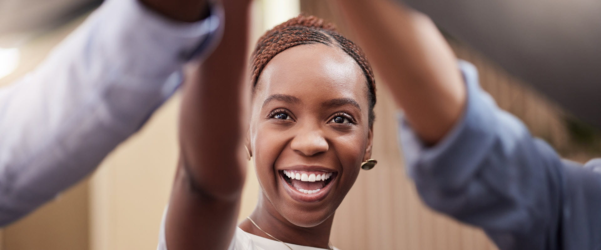 A young worker smiles as they high-five other workers out of frame A young worker smiles as they high-five other workers out of frame