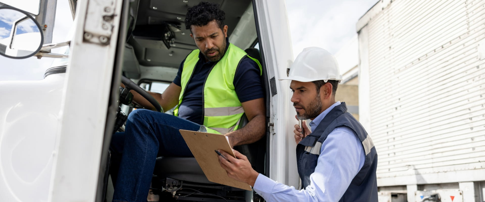 Foreperson talking to a truck driver while working at a distribution warehouse transporting merchandise