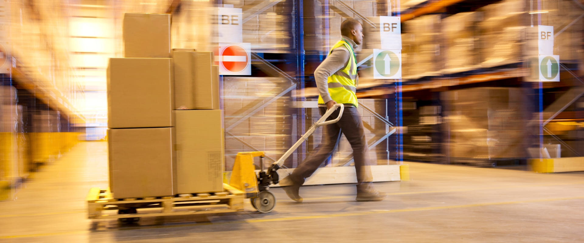 Blurred view of worker carting boxes in warehouse