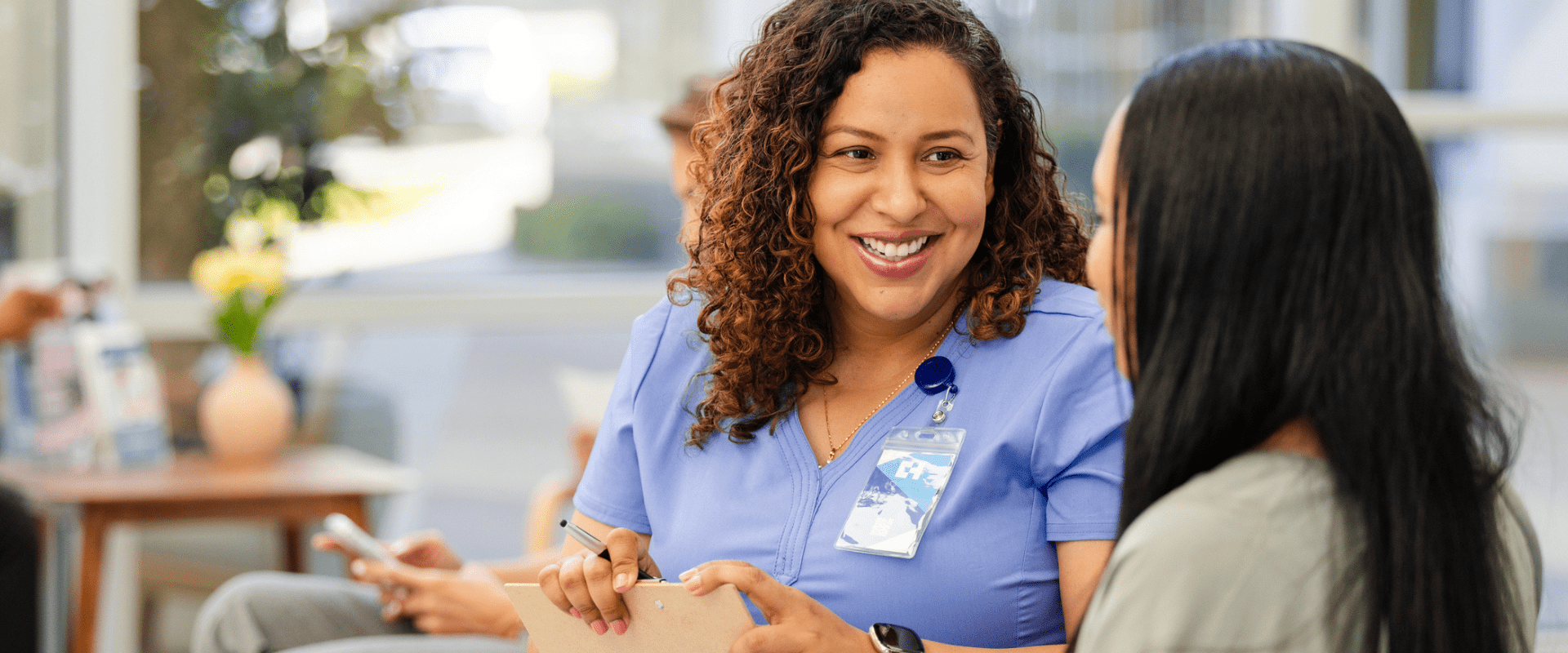 A nurse sits in a waiting room, listening to a patient