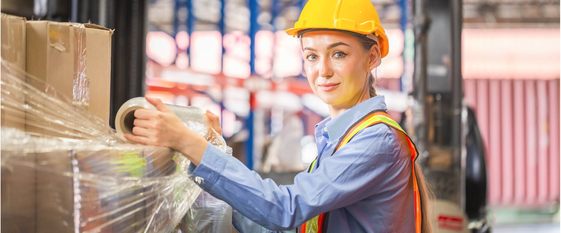 Worker wrapping boxes in stretch film at warehouse. Worker wrapping boxes in stretch film at warehouse.